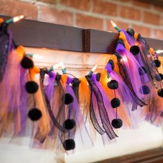 colorful streamers and pom - poms hanging from a mantle