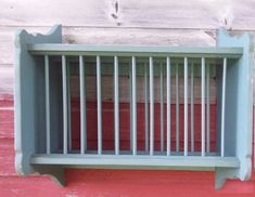 a window sill with bars on the side of it in front of a red wall