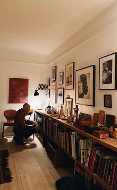 a living room filled with lots of books and pictures on the wall next to a wooden floor