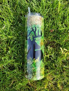 a tumbler cup sitting in the grass with an image of a deer on it