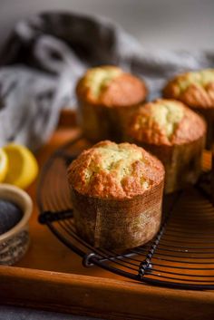 several muffins sitting on a cooling rack with lemon wedges next to them