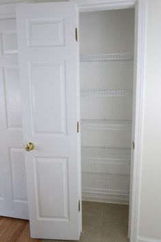 an empty closet with white doors and shelves