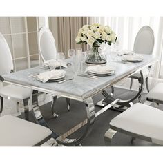 a dining room table with white chairs and plates