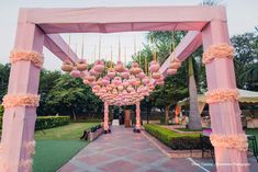 an outdoor wedding venue with pink decorations and flowers hanging from the ceiling, surrounded by lush greenery