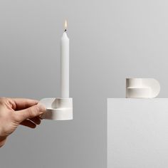 a person holding a lit candle in front of a white box with a ring on it