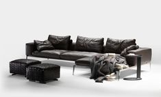 a black leather couch sitting next to a chair and ottoman on top of a white floor