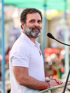 a man standing at a podium in front of a microphone with his hand on the edge