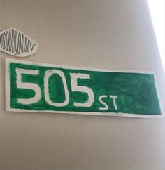 a green street sign sitting on the side of a wall next to a sticker