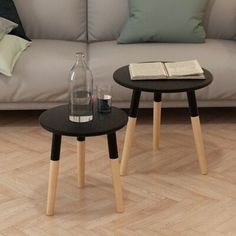 two small wooden tables sitting on top of a hard wood floor next to a couch