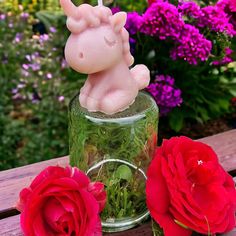 a glass jar filled with flowers next to two red roses on top of a wooden table