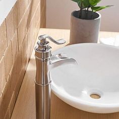 a white sink sitting on top of a wooden counter next to a potted plant