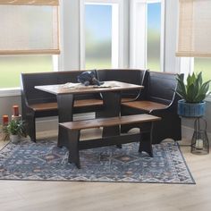 a corner table with benches in front of two windows and a rug on the floor