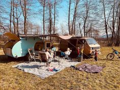 some people are sitting at a picnic table in front of an rv and camper