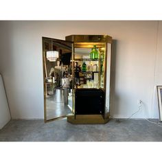 a tall gold cabinet sitting inside of a room next to a wall mounted tv and a mirror