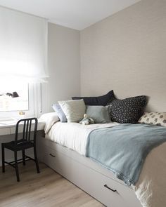 a bedroom with a bed, desk and chair next to each other in front of a window