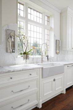 a kitchen with white cabinets and wooden counter tops, along with a window over the sink