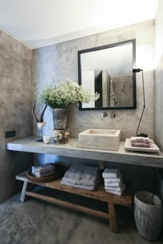 a bathroom with a sink, mirror and towels on the shelf in front of it