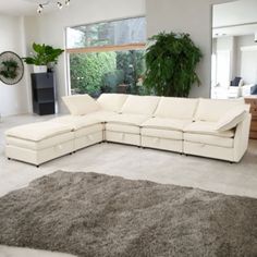 a living room with a large white sectional couch and rug on the floor in front of a window