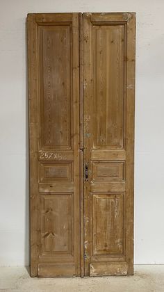 an old pair of wooden doors sitting on top of a white floor next to a wall