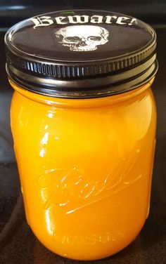 a jar filled with yellow liquid sitting on top of a black counter next to a stove