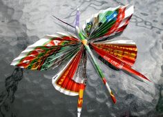 a colorful paper butterfly floating on top of the water with its wings spread out to dry