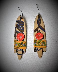 two wooden surfboards with designs on them hanging from hooks and ear wires against a white wall