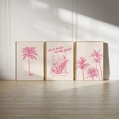 three pink and white paintings on wooden floors in front of a wall with palm trees