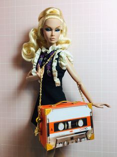 a barbie doll holding an orange and white cassette bag