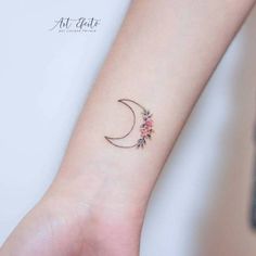 a woman's wrist with a small flowered crescent tattoo on her left arm