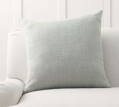 a white couch with a light gray pillow on it's back and armrests