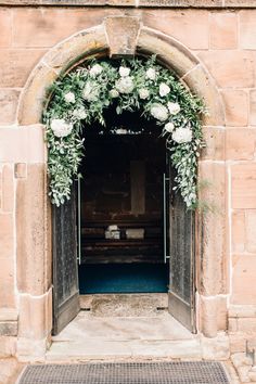 an archway with flowers and greenery on the door way to a wedding ceremony at st mary's church