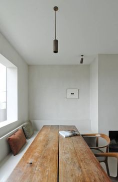 a long wooden table sitting in the middle of a room with two chairs next to it