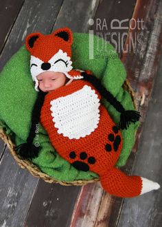 a baby sleeping in a basket with a fox on it