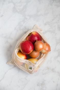 a bag filled with apples sitting on top of a white counter