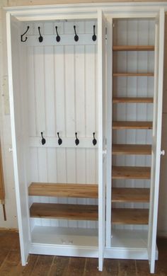 an empty white closet with wooden shelves and hooks