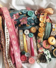 many different types of buttons and ribbons on a bed