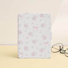 a pair of glasses sitting on top of a table next to a case with pink flowers