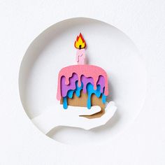 a piece of paper with a cake on it and a candle sticking out of it