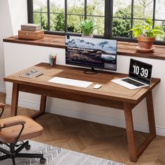 a wooden desk with a computer monitor and laptop on it in front of a window