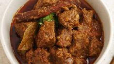 a close up of a bowl of food with meat and vegetables in sauce on the side