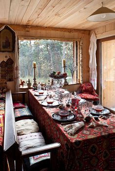 a dining room table is set with place settings and candles on the windowsills