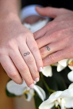 two people holding hands with tattoos on their fingers