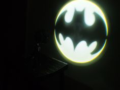 a batman logo is projected on the wall in front of a dark room with a spotlight