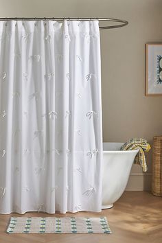 a white shower curtain with dragonflies on it in a bathroom next to a bathtub