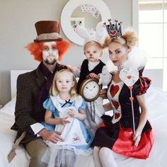 three adults and two children dressed up as alice and the wonderland characters on a bed