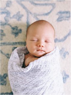 a baby wrapped in a blanket on top of a rug