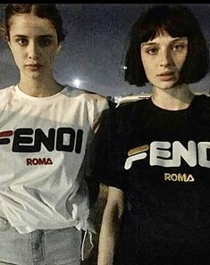 two young women standing next to each other in front of a dark background with the word fend on it