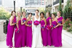 a group of women standing next to each other wearing purple dresses and holding bouquets