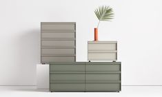 three drawers and a plant on top of each other in front of a white wall