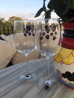 two wine glasses sitting on top of a wooden table next to a potted plant